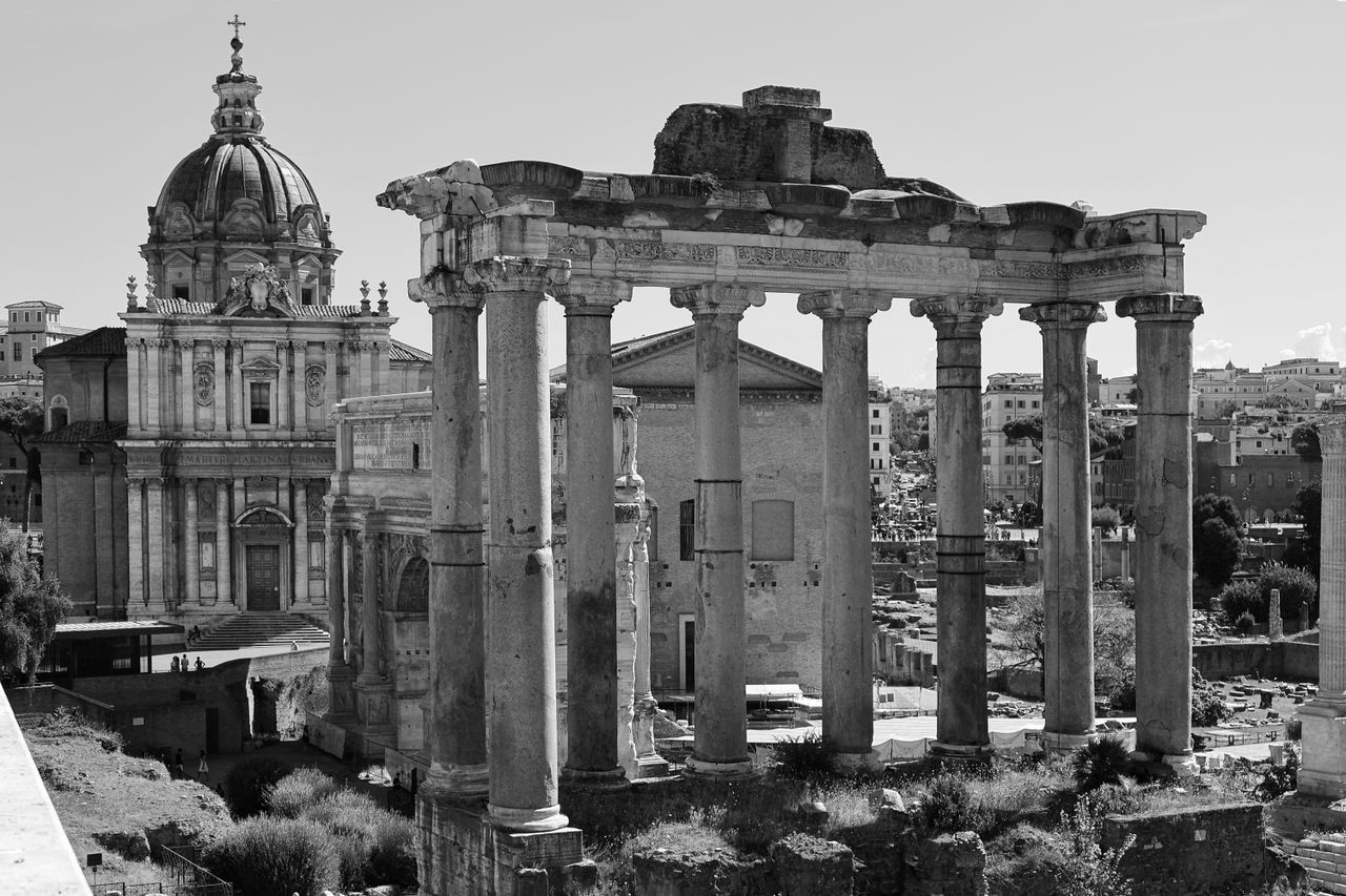 Black and white photo of ancient Roman Forum ruins with church in Rome, Italy.