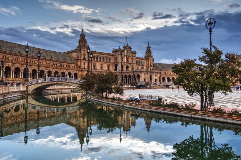Captivating reflection of Plaza de España in Seville, showcasing architectural beauty and serene water reflections.