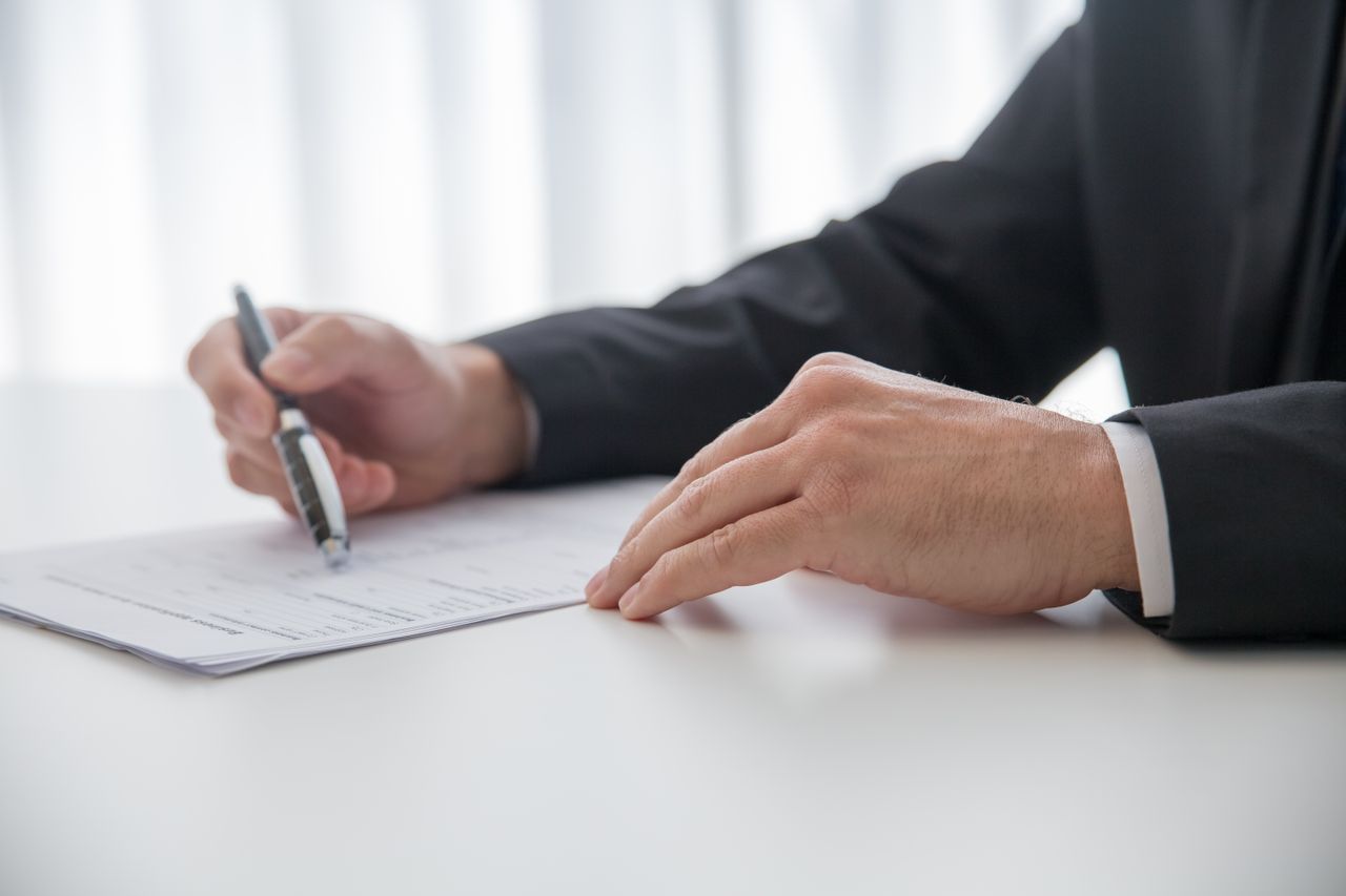 Businessman signing important documents at office desk.